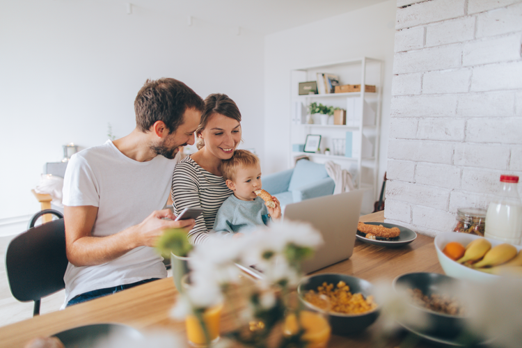 Mother, Father, and Child sit at the kitchen table looking at a laptop